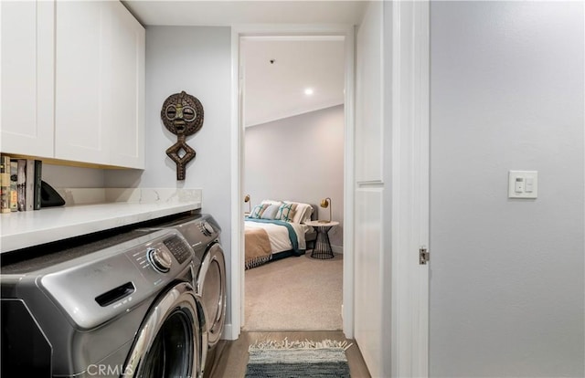 washroom with carpet flooring, washing machine and dryer, and cabinet space