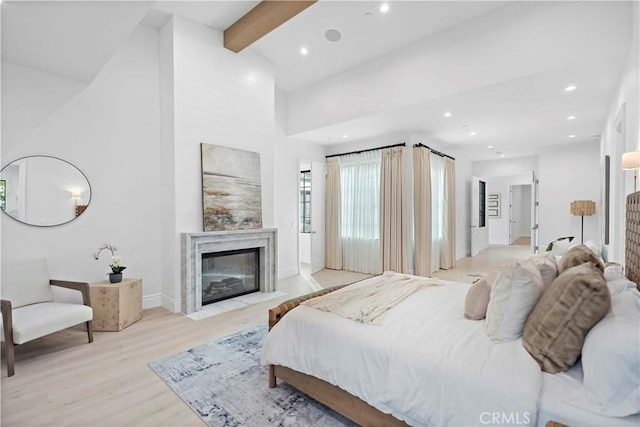 bedroom featuring vaulted ceiling with beams and light hardwood / wood-style flooring