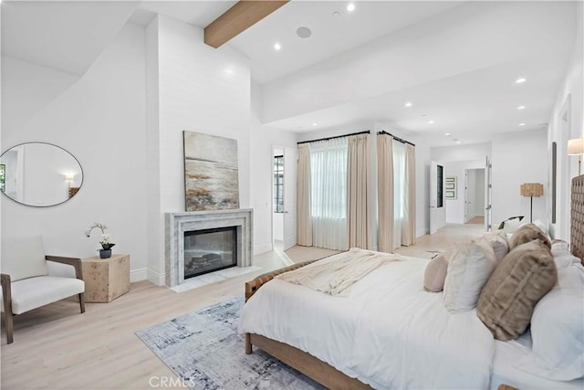 bedroom featuring beam ceiling, high vaulted ceiling, recessed lighting, light wood-style floors, and a fireplace