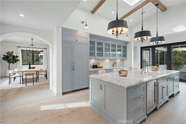 kitchen featuring beverage cooler, a notable chandelier, gray cabinets, and a sink