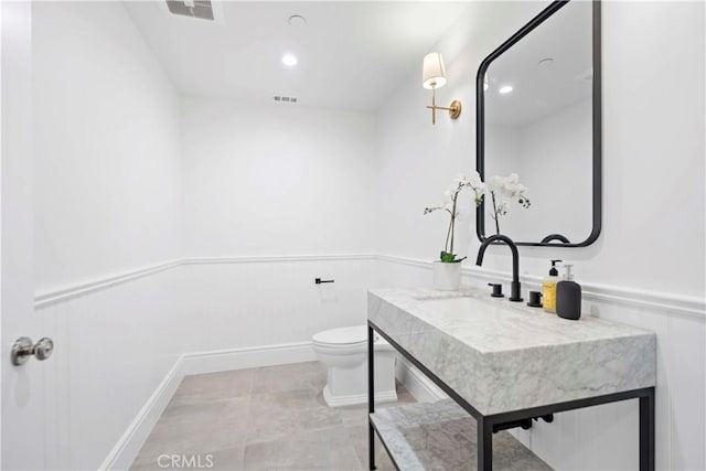 bathroom with visible vents, vanity, toilet, and wainscoting