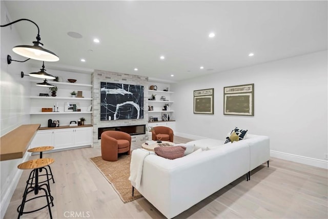 living area featuring built in features, baseboards, light wood-style floors, and recessed lighting