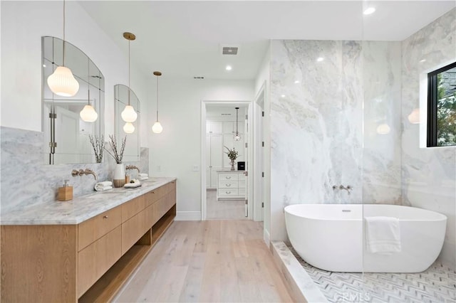 bathroom with visible vents, a freestanding bath, recessed lighting, wood finished floors, and vanity