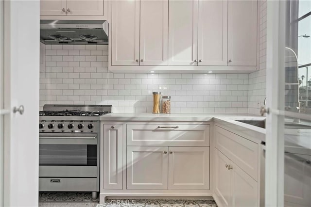 kitchen featuring backsplash, ventilation hood, stainless steel range with gas cooktop, light countertops, and white cabinetry