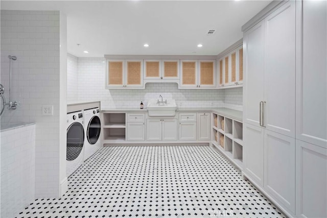 clothes washing area with light floors, recessed lighting, washer and dryer, cabinet space, and a sink