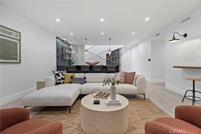 living room with bar area and light hardwood / wood-style flooring