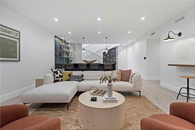 living room featuring recessed lighting, visible vents, light wood-type flooring, and stairway