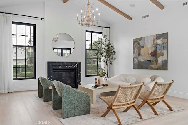 sitting room with light wood-style flooring, high vaulted ceiling, an inviting chandelier, and a premium fireplace