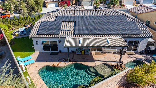 back of house featuring a patio area, a pool with hot tub, and solar panels