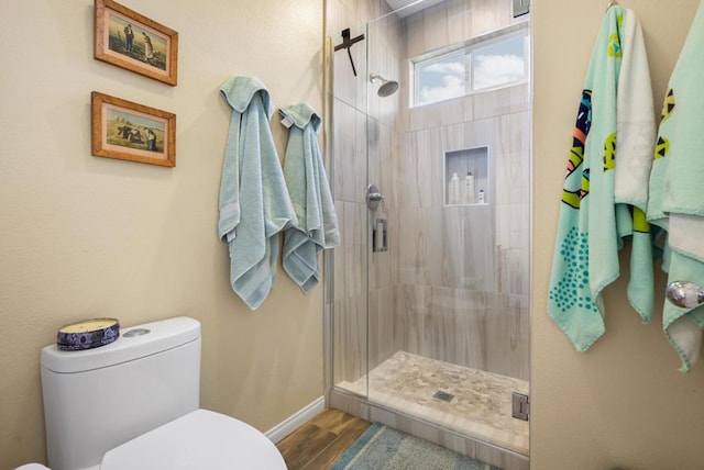 bathroom with toilet, wood-type flooring, and a shower with door