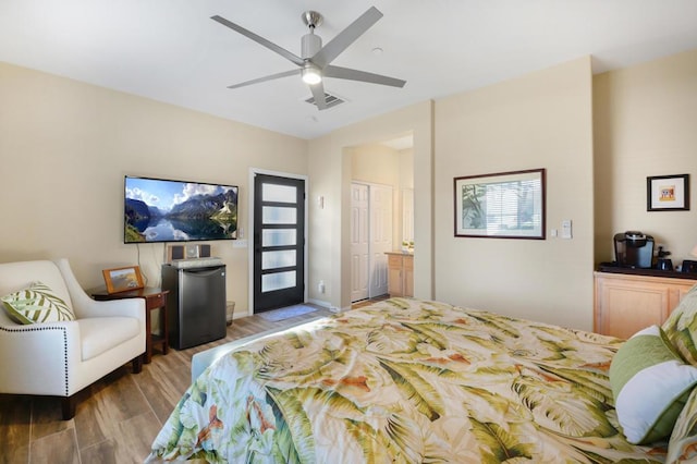 bedroom featuring hardwood / wood-style floors, a closet, refrigerator, ceiling fan, and ensuite bathroom