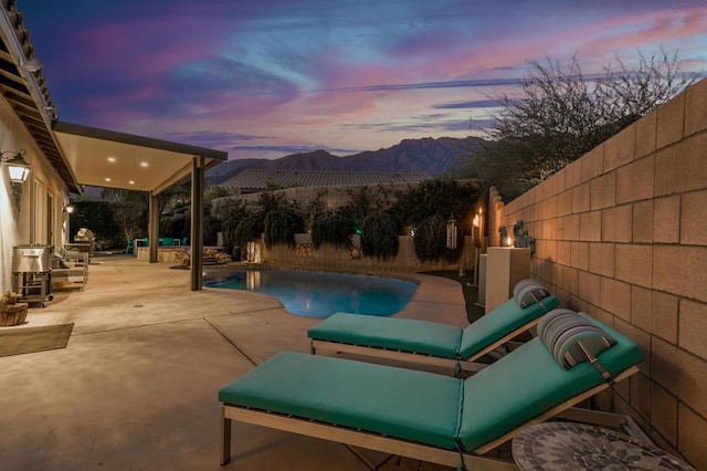 pool at dusk with a mountain view and a patio area