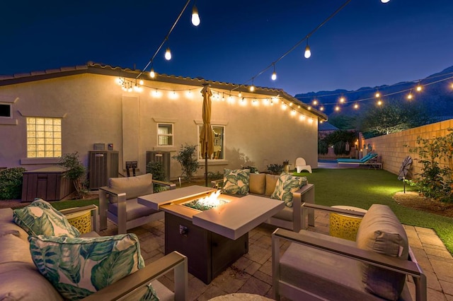 patio at night featuring central AC, an outdoor living space with a fire pit, and a lawn