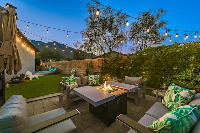 patio terrace at dusk with a lawn and an outdoor living space with a fire pit