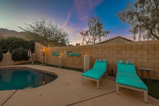 pool at dusk featuring a patio area, sink, and a mountain view