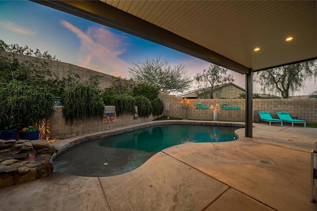 pool at dusk featuring a patio