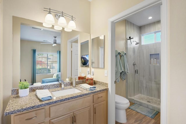 bathroom featuring toilet, hardwood / wood-style floors, a shower with door, ceiling fan, and vanity