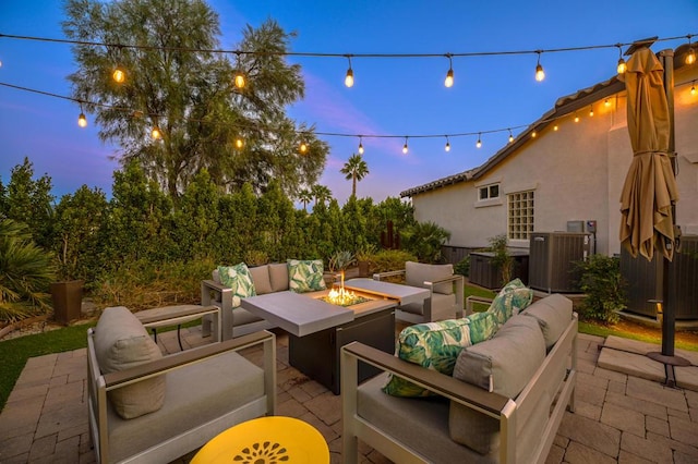 patio terrace at dusk with central AC unit and an outdoor living space with a fire pit