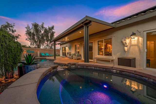 pool at dusk featuring a jacuzzi and a patio