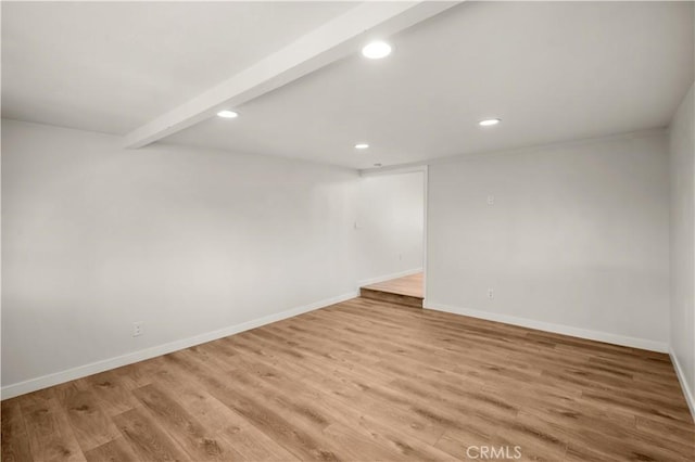 empty room with light wood-type flooring and beamed ceiling