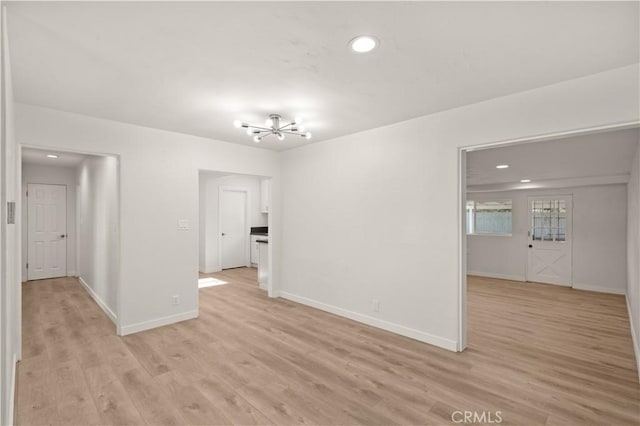 spare room featuring light hardwood / wood-style floors and an inviting chandelier