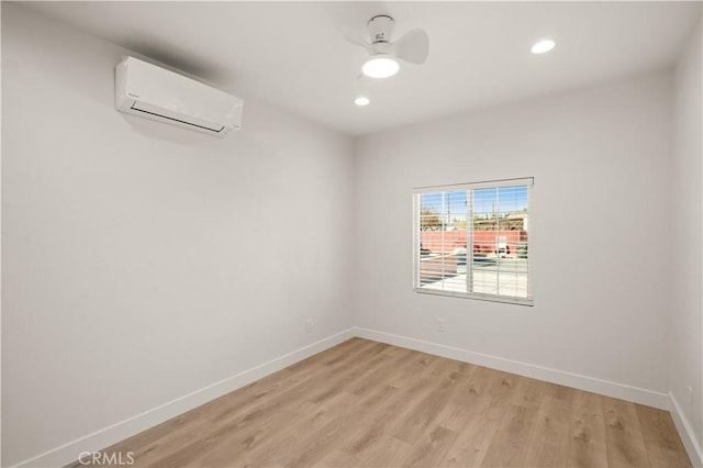 empty room with ceiling fan, light hardwood / wood-style floors, and a wall mounted air conditioner