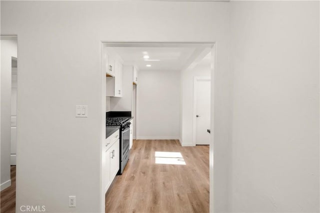 kitchen with white cabinetry, light hardwood / wood-style flooring, and stainless steel range with gas stovetop