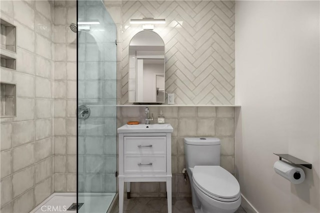 bathroom featuring tile walls, tiled shower, vanity, and toilet