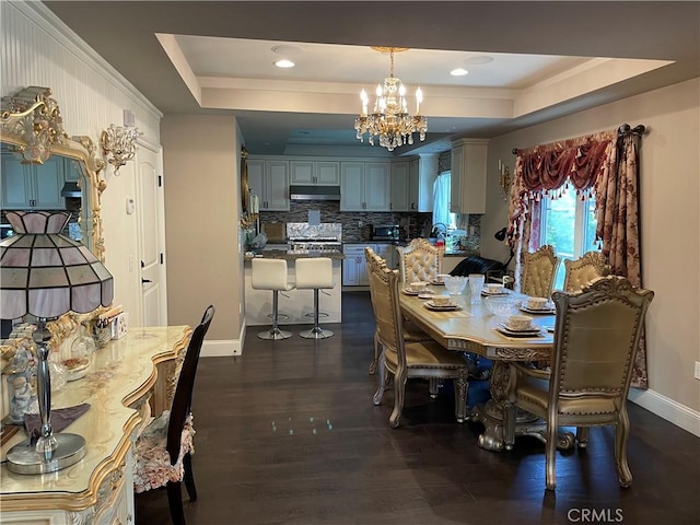 dining space featuring a raised ceiling, dark wood-type flooring, and an inviting chandelier