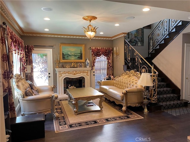 living room featuring a fireplace, an inviting chandelier, ornamental molding, and hardwood / wood-style flooring