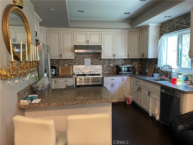 kitchen with kitchen peninsula, sink, white cabinets, and appliances with stainless steel finishes