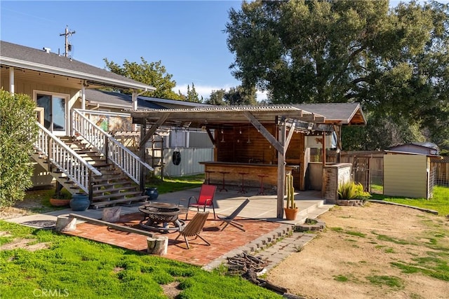 back of house with exterior bar, a patio area, a fire pit, and a storage unit