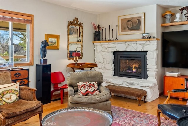 living area with light hardwood / wood-style floors and a stone fireplace