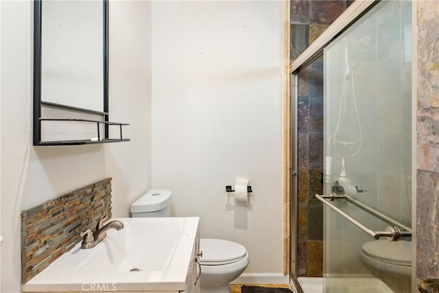 bathroom featuring a shower with shower door, toilet, and vanity