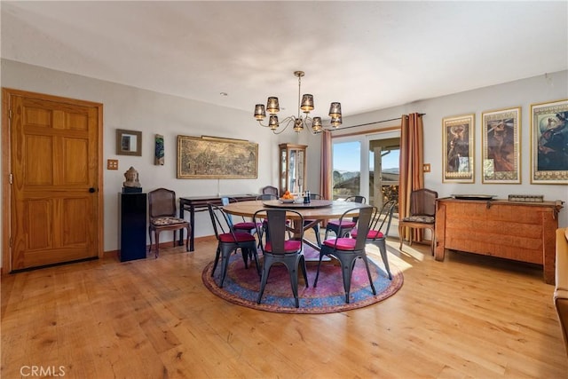 dining area with light wood-type flooring and a chandelier