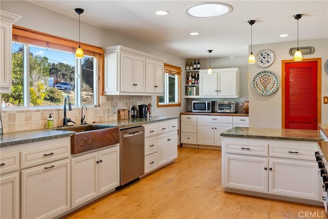 kitchen with white cabinets, hanging light fixtures, appliances with stainless steel finishes, and sink