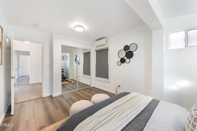 bedroom with a closet, a wall mounted AC, and wood-type flooring