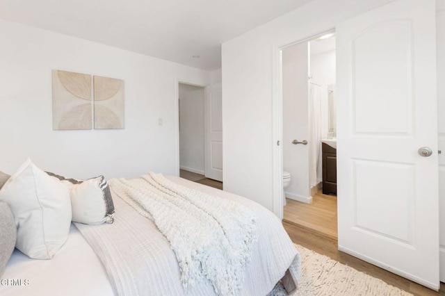 bedroom with connected bathroom and light wood-type flooring