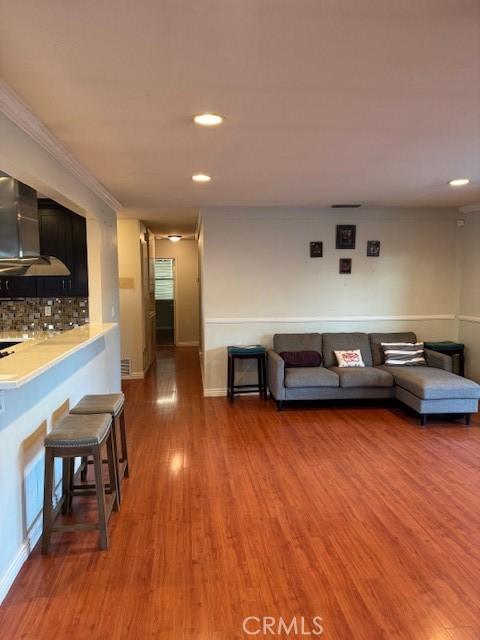 unfurnished living room with wood-type flooring and crown molding