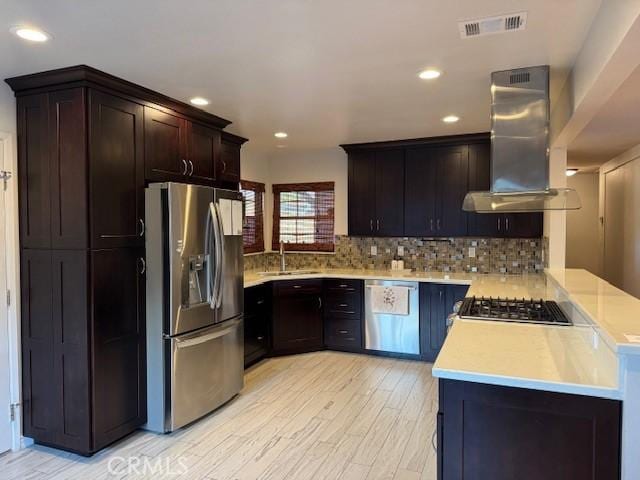 kitchen featuring stainless steel appliances, sink, backsplash, kitchen peninsula, and island range hood