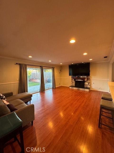 living room with hardwood / wood-style floors, crown molding, and a fireplace