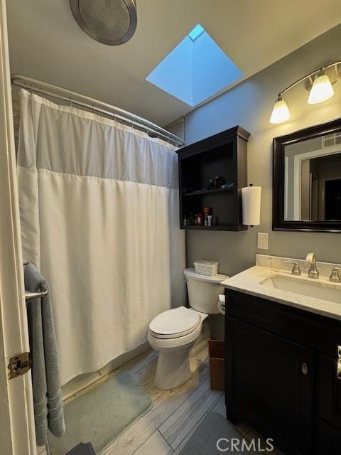 bathroom featuring hardwood / wood-style floors, toilet, vanity, and a shower with curtain