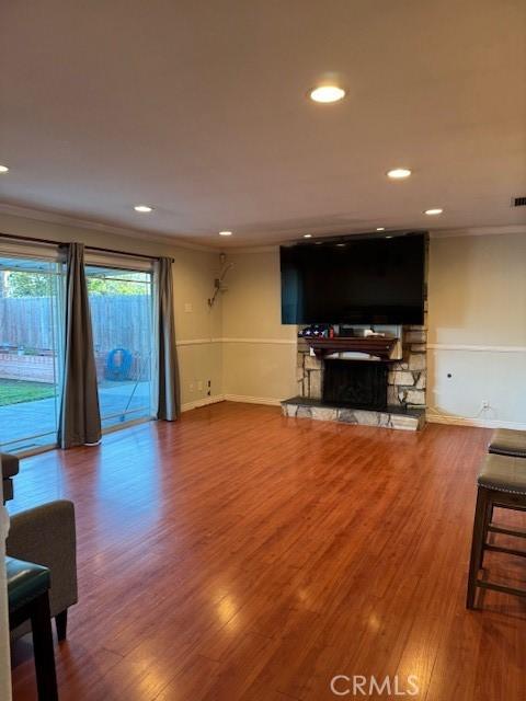 living room featuring a fireplace, crown molding, and hardwood / wood-style flooring