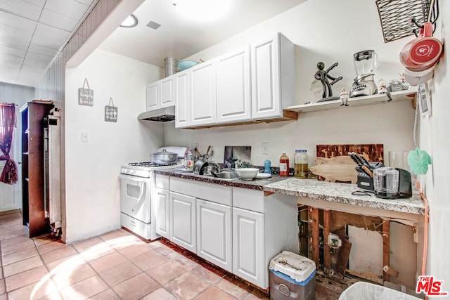 kitchen featuring sink, white cabinetry, light tile patterned floors, and white gas range oven