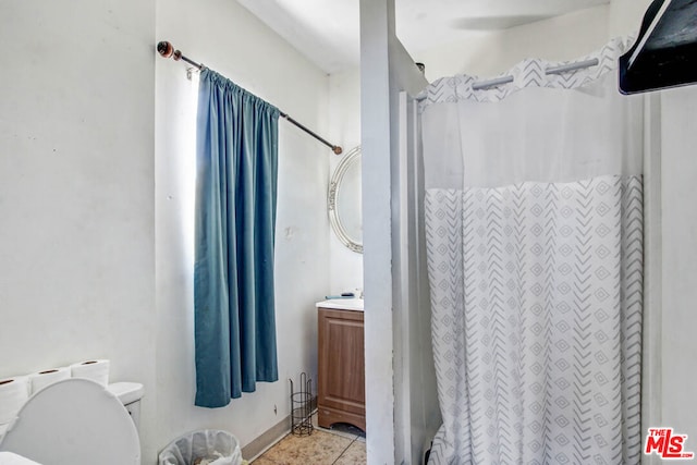 bathroom featuring toilet, tile patterned flooring, vanity, and curtained shower