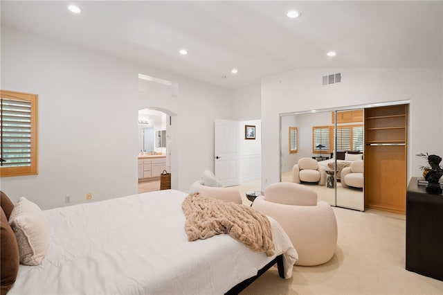 carpeted bedroom with a closet, lofted ceiling, and connected bathroom