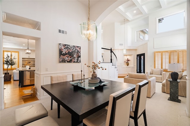 dining room featuring beam ceiling, a towering ceiling, and a notable chandelier