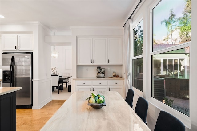 dining space with crown molding and light hardwood / wood-style flooring