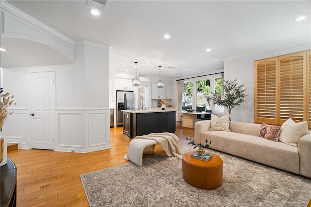 living room featuring sink, crown molding, and hardwood / wood-style flooring