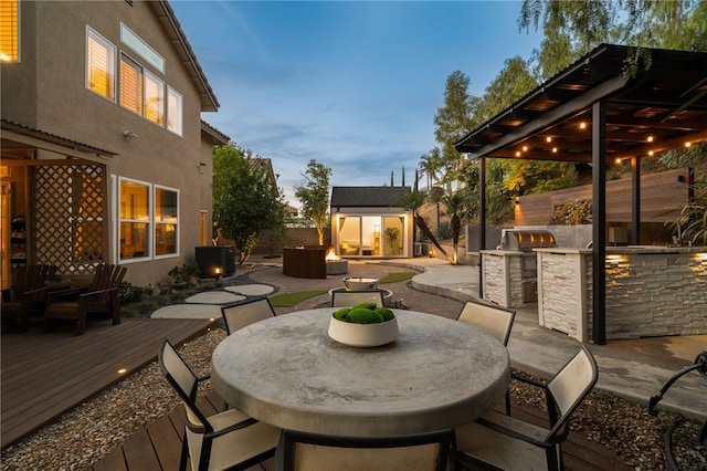 patio terrace at dusk featuring grilling area, an outbuilding, central air condition unit, a wooden deck, and area for grilling